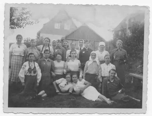Group photograph of young women in front of wooden houses, taken in the German Reich.